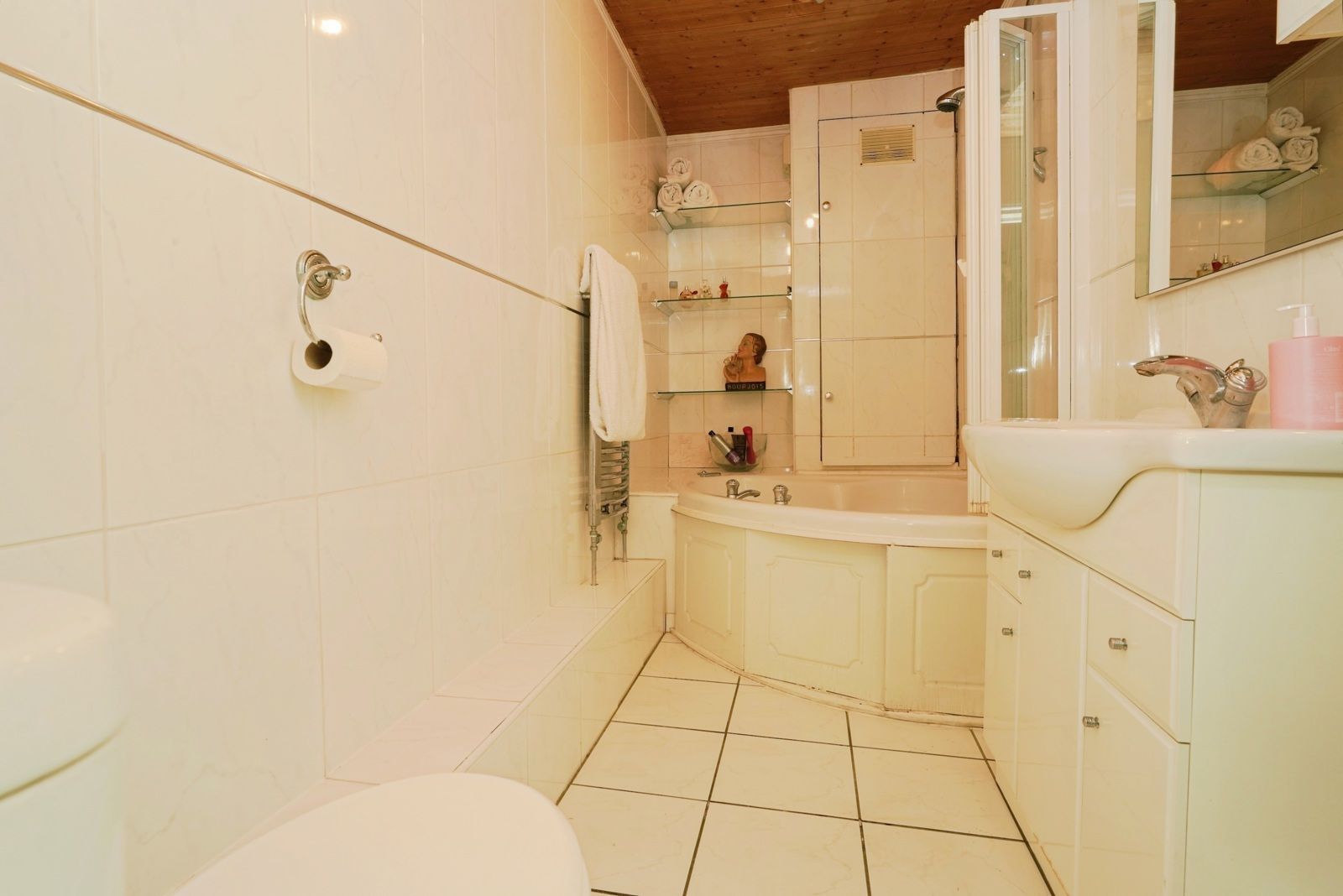 Bathroom with a corner bath, basin and tiled floor