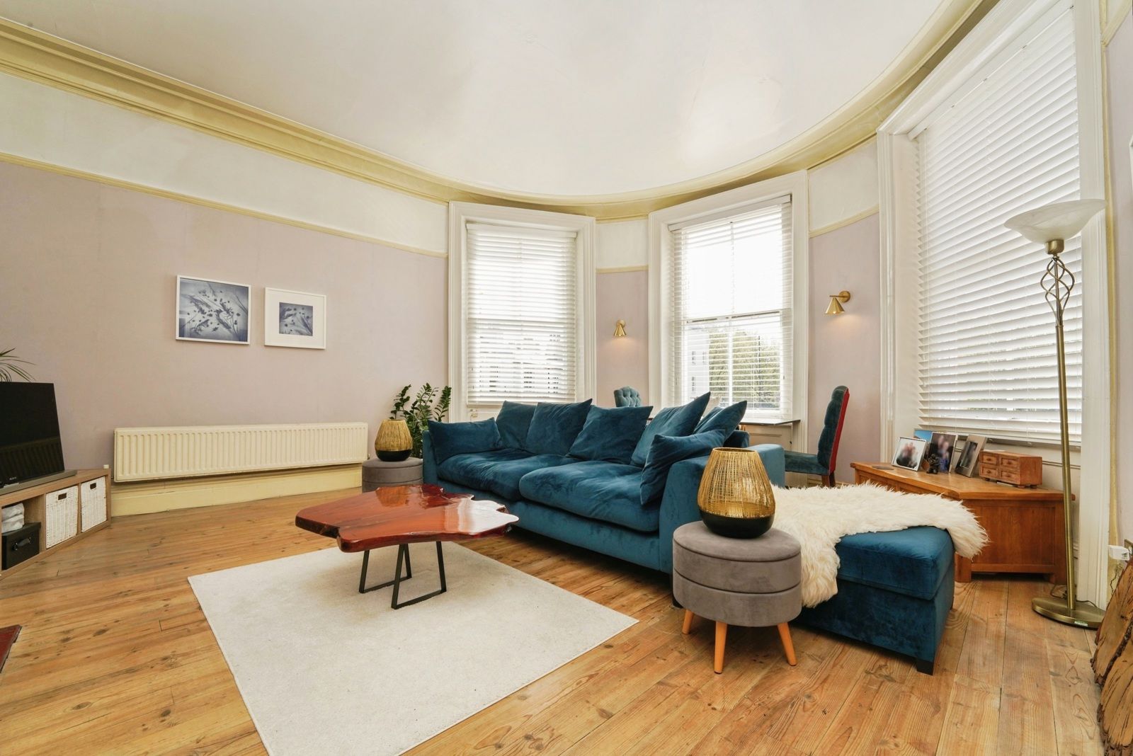 Lounge with sofa, coffee table and standard lamp, wood floor throughout