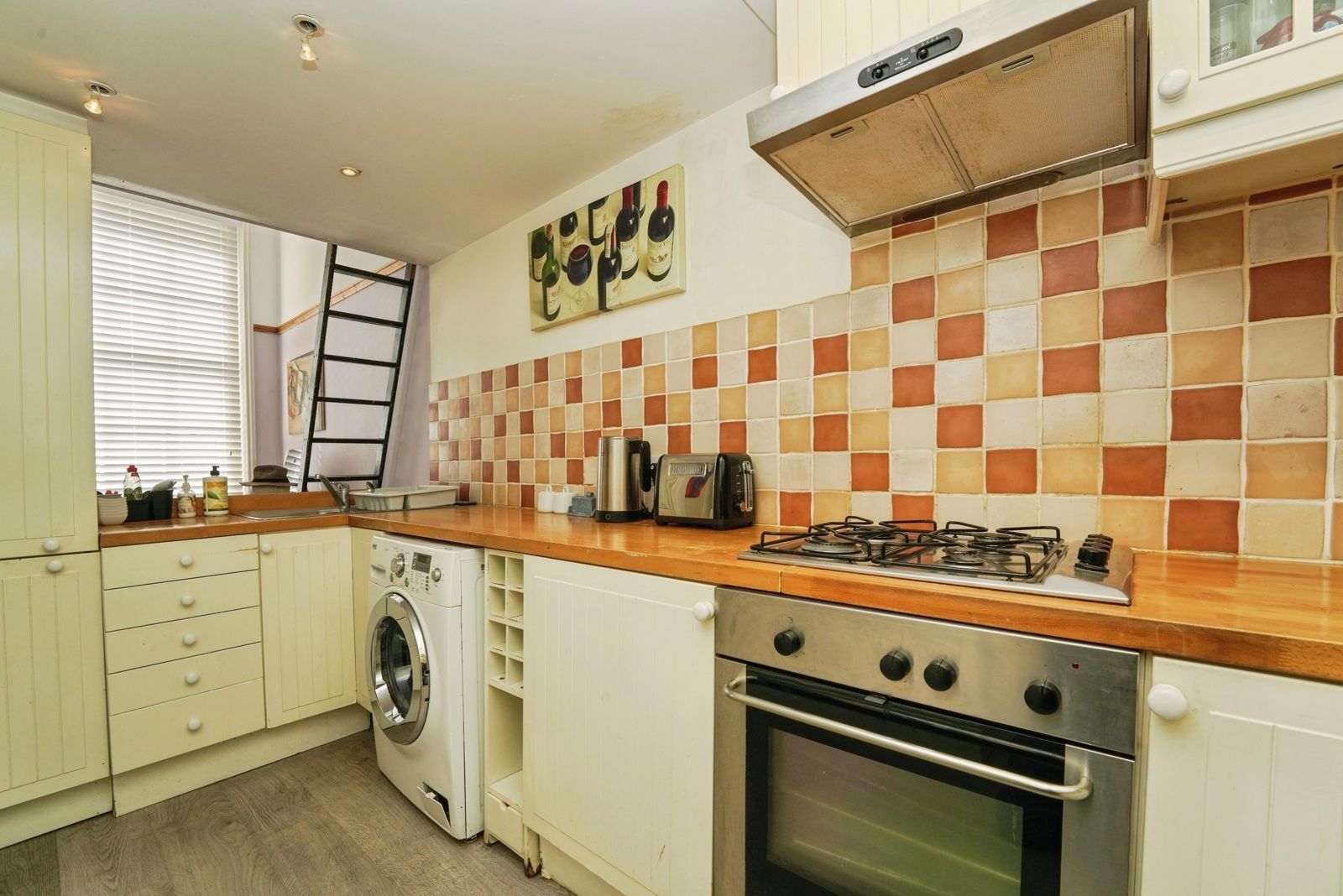 Galley kitchen with gas hob, oven, extractor and tiled splashback