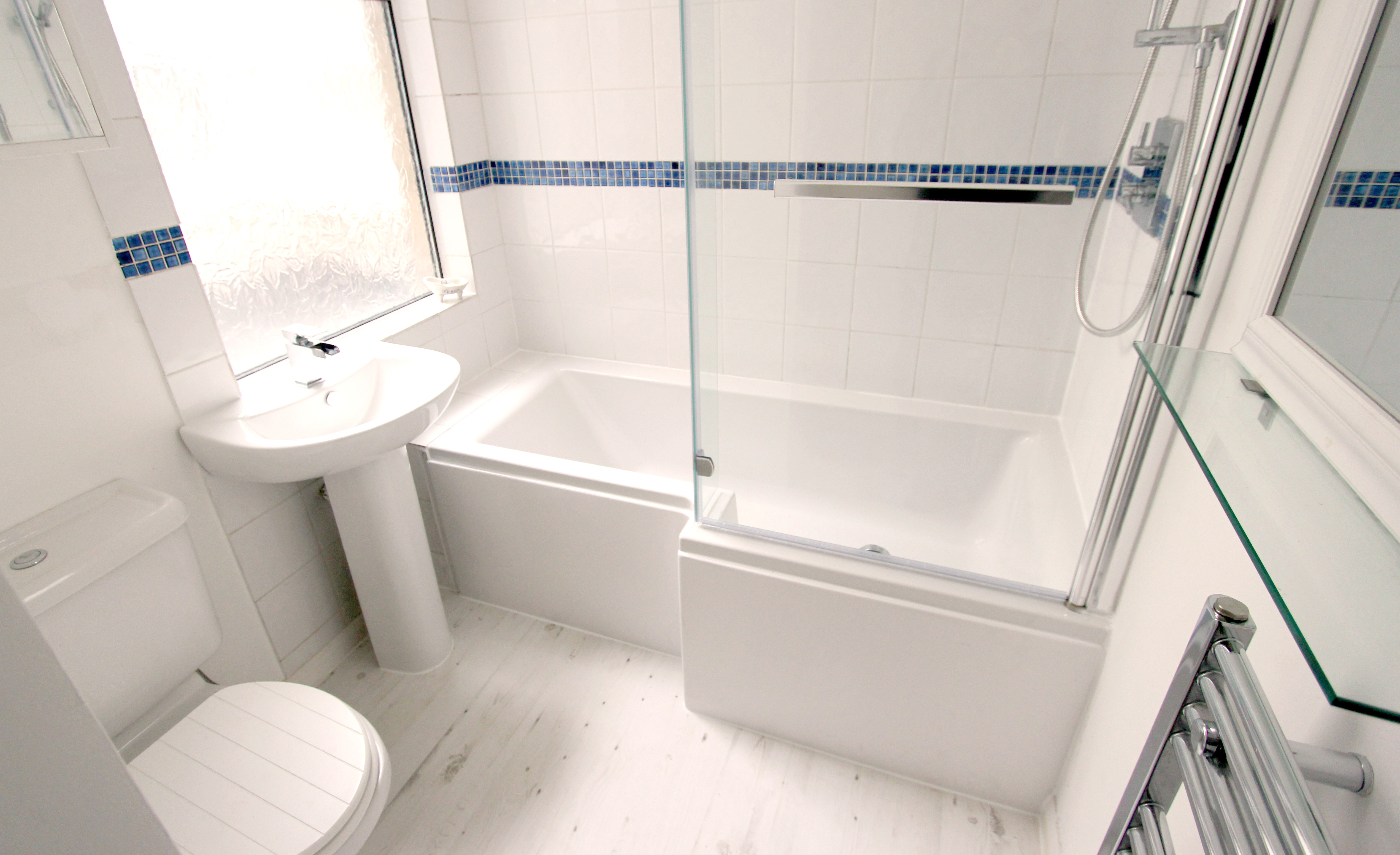 Refitted bathroom with a bath, shower over and glass screen
