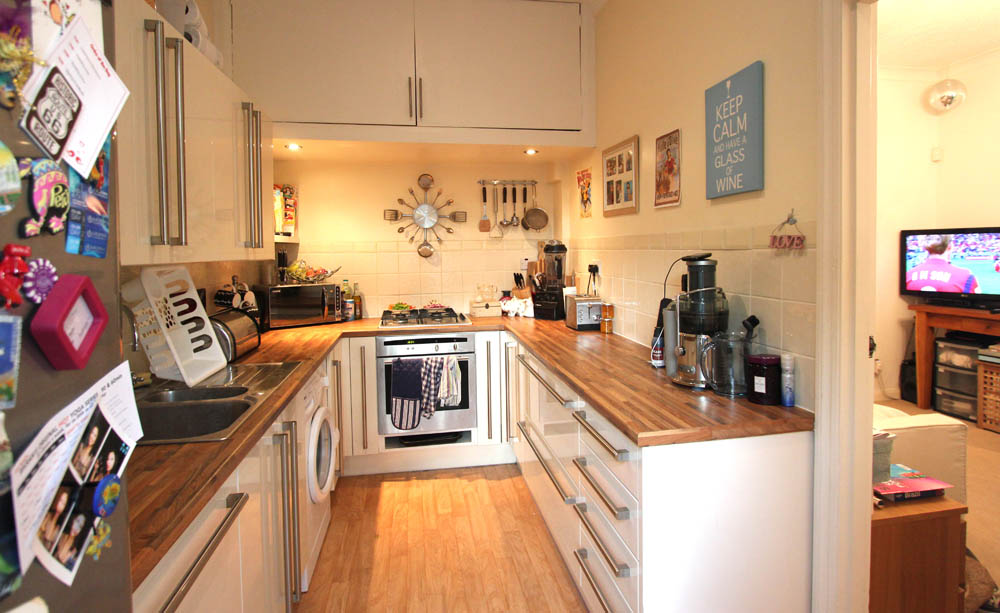 Galley kitchen with fitted units on both sides, gas hob and oven